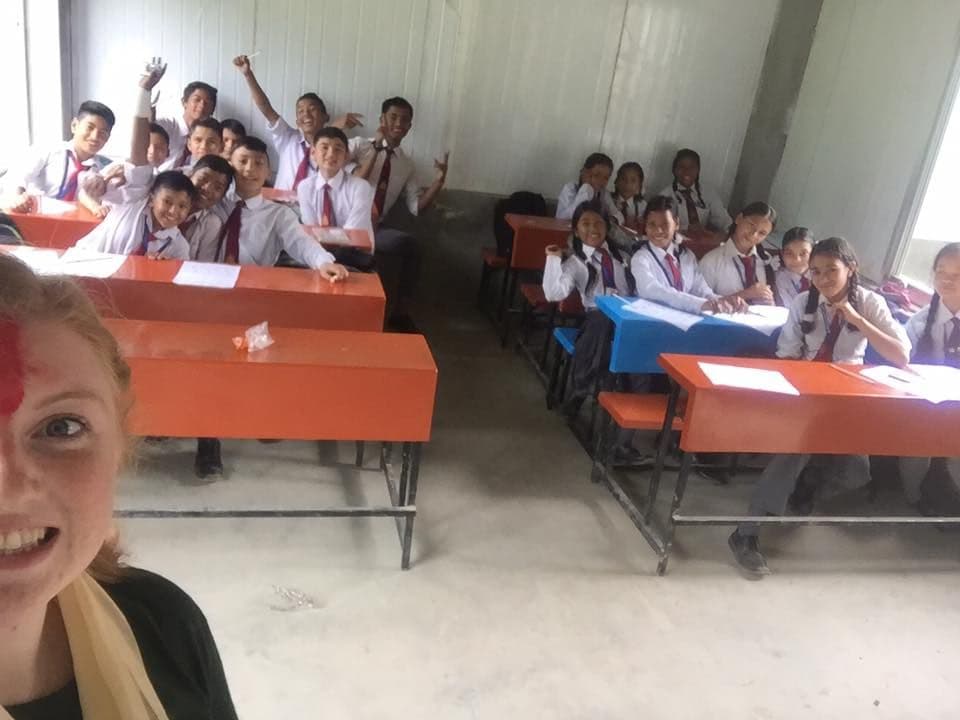 A group of students in uniforms posing for a photo with a Hollie in the foreground.